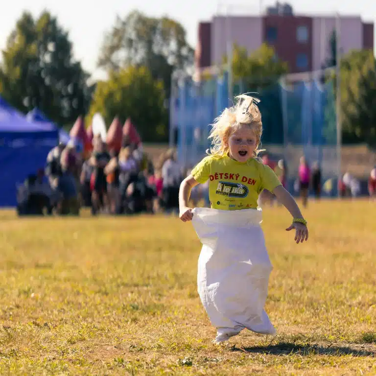 Enfant joyeux participant à une course en sac sur une pelouse lors d'un événement d'entreprise Family Day animé