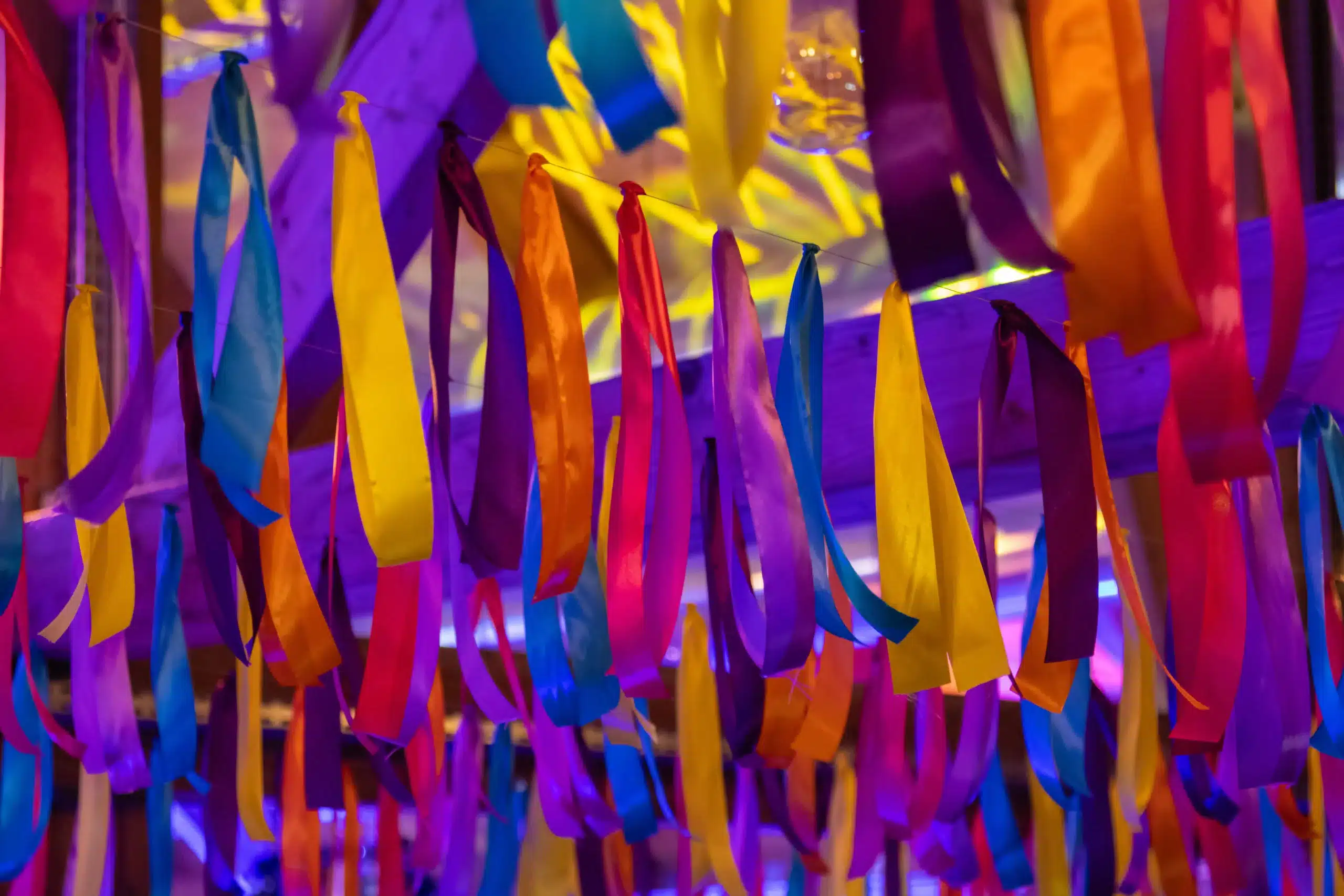 Plafond d'une soirée d'entreprise nantaise décoré de rubans colorés suspendus (jaune, violet, bleu, rose) pour une ambiance de Carnaval brésilien signée l'Agence Helper.