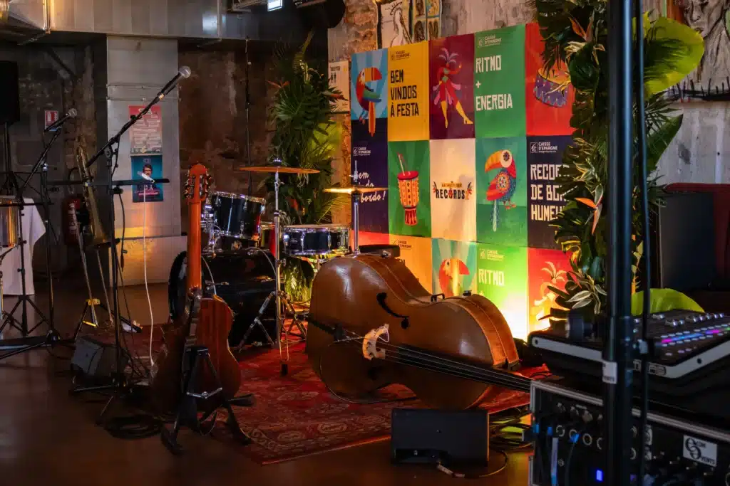 Scène de musique brésilienne pour événement d'entreprise à Nantes : contrebasse, guitare et batterie installées devant un mur de décors colorés et végétaux tropicaux.