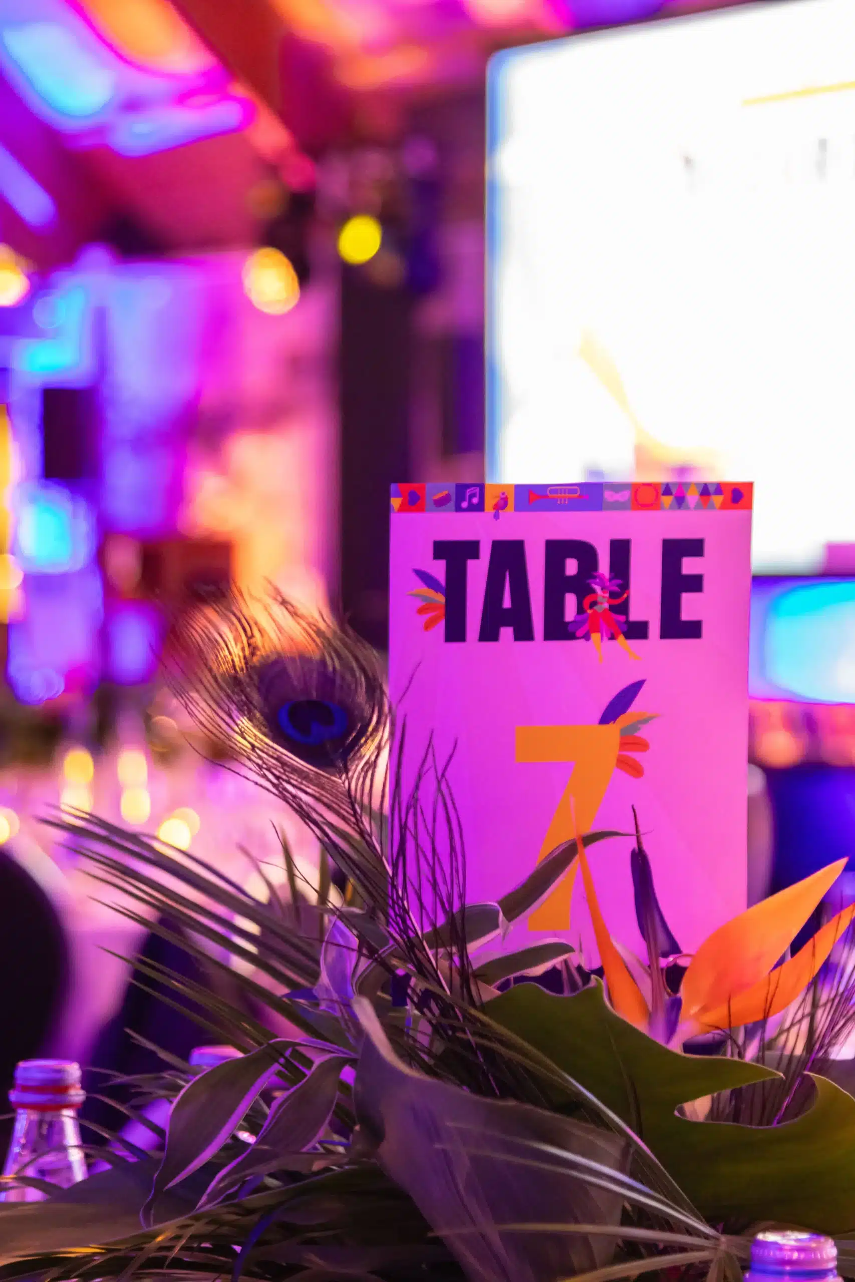 Centre de table tropical pour soirée d'entreprise à Nantes : plume de paon, fleurs exotiques et menu personnalisé de l'Agence Helper pour un cocktail dînatoire brésilien.